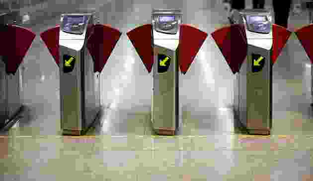 Turnstiles with red flags attached in a row at an entrance. Turnstiles with red flags attached in a row at an entrance.