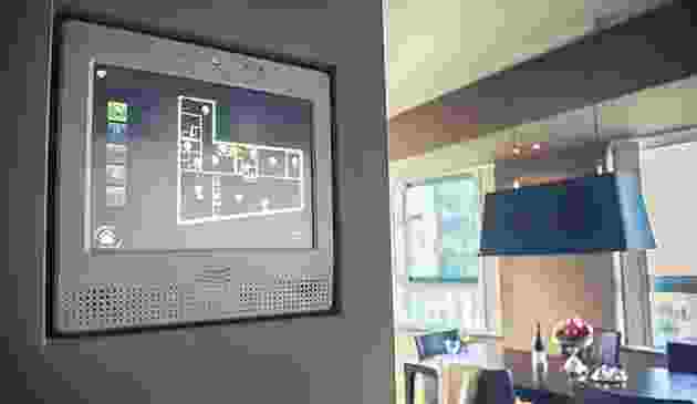 A digital smart home control panel on a wall in a modern living room. A digital smart home control panel on a wall in a modern living room.