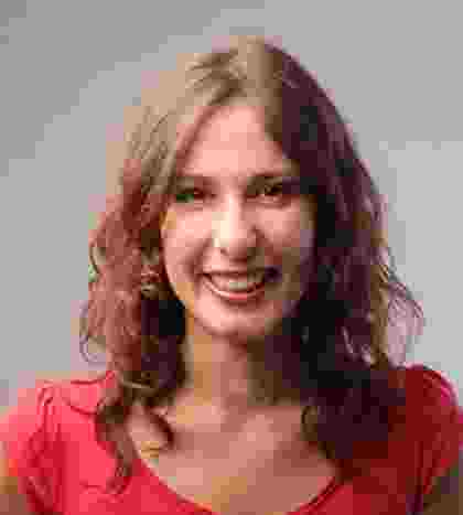 A smiling woman with curly hair wearing a red top. A smiling woman with curly hair wearing a red top.