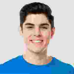 A young man smiling wearing a blue shirt against a plain background. A young man smiling wearing a blue shirt against a plain background.