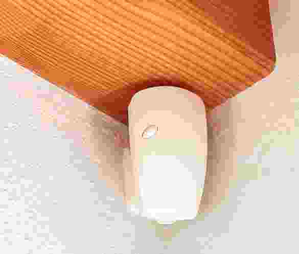 A close-up of a fingernail with a white French tip design. A close-up of a fingernail with a white French tip design.