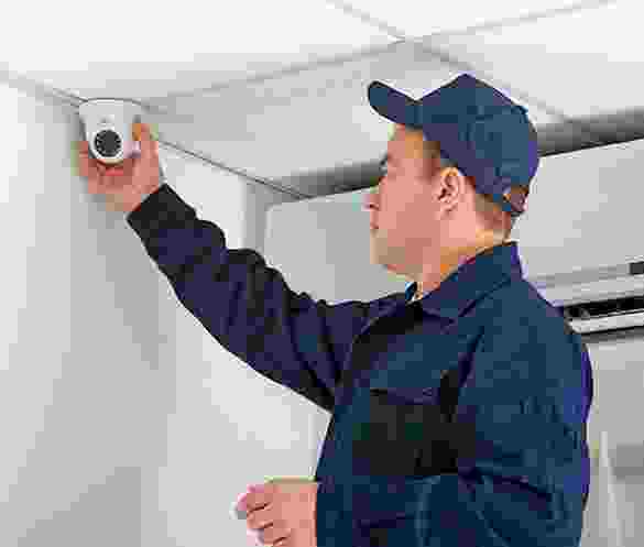 Technician installing a security camera on a ceiling. Technician installing a security camera on a ceiling.