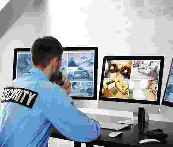 Security guard monitoring surveillance cameras on multiple screens. Security guard monitoring surveillance cameras on multiple screens.
