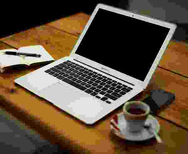 Laptop, coffee cup, and notebook on a wooden table. Laptop, coffee cup, and notebook on a wooden table.