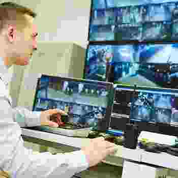 Man monitoring multiple security camera feeds on several screens. Man monitoring multiple security camera feeds on several screens.