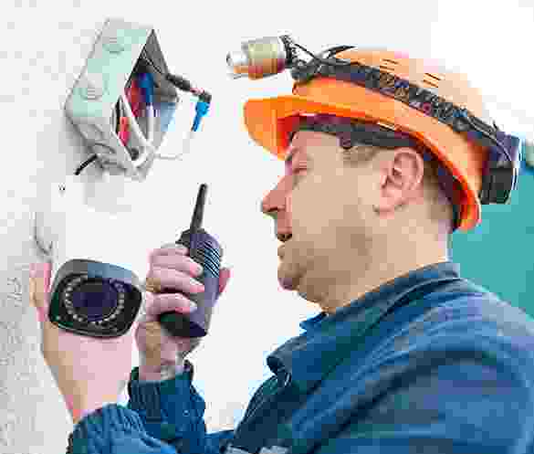 Technician installing or inspecting security cameras using a walkie-talkie. Technician installing or inspecting security cameras using a walkie-talkie.