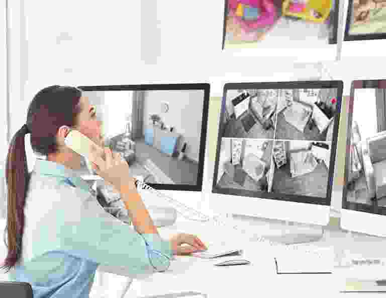 Woman monitoring security cameras while talking on the phone. Woman monitoring security cameras while talking on the phone.