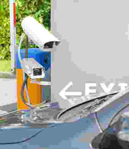 Car parked at an electric vehicle charging station with visible charging cable. Car parked at an electric vehicle charging station with visible charging cable.