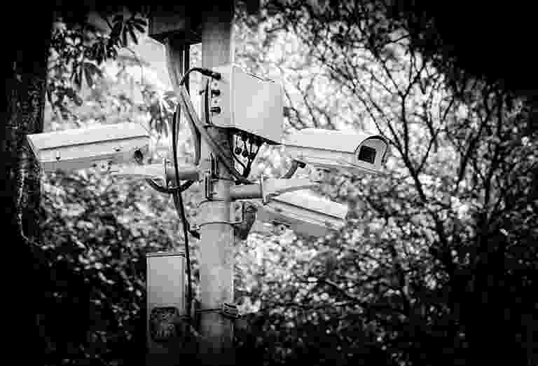 Black and white photo of multiple surveillance cameras on a pole. Black and white photo of multiple surveillance cameras on a pole.
