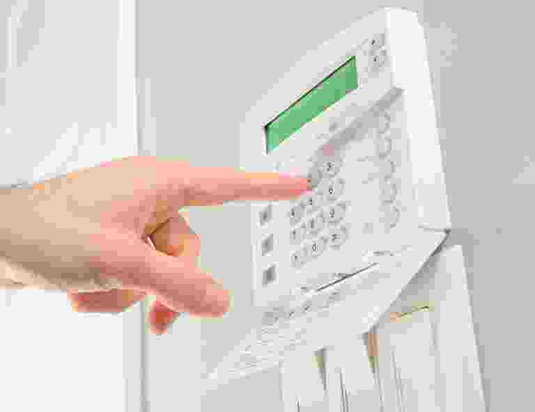 Finger pressing buttons on a home security alarm keypad. Finger pressing buttons on a home security alarm keypad.