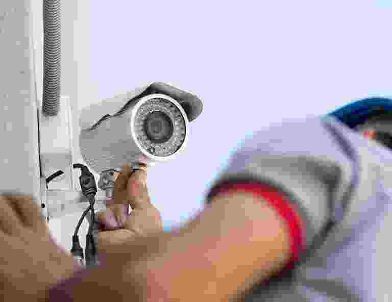 Person adjusting a security camera on the wall. Person adjusting a security camera on the wall.