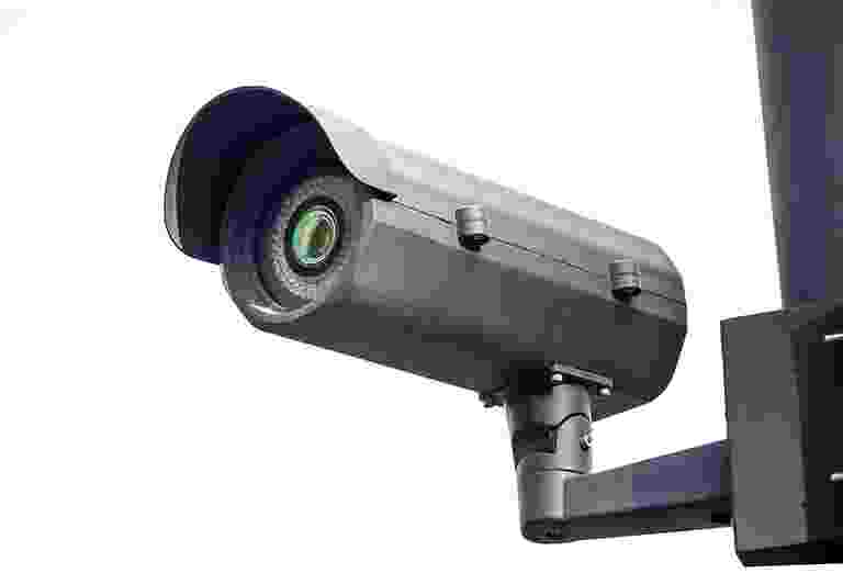 A modern security camera mounted on a wall bracket. A modern security camera mounted on a wall bracket.