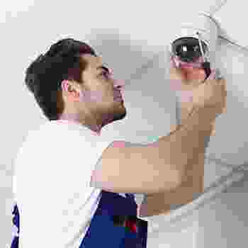 Technician installing a security camera on a ceiling. Technician installing a security camera on a ceiling.