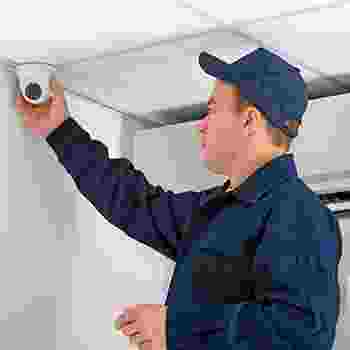 Technician installing a security camera indoors on the ceiling. Technician installing a security camera indoors on the ceiling.