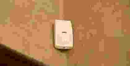 A white wall-mounted soap dispenser in a bathroom. A white wall-mounted soap dispenser in a bathroom.
