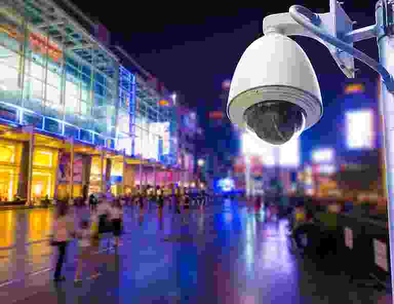 A surveillance camera monitoring a busy urban street at night. A surveillance camera monitoring a busy urban street at night.