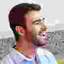 A man smiling joyfully with eyes closed against a stone wall. A man smiling joyfully with eyes closed against a stone wall.