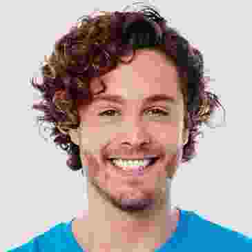 Smiling young man with curly hair and blue shirt.
