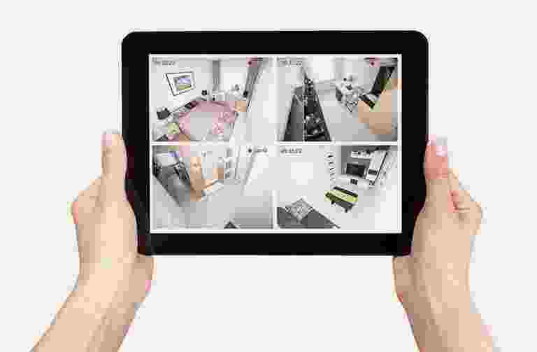 Person holding tablet showing four surveillance camera views indoors. Person holding tablet showing four surveillance camera views indoors.