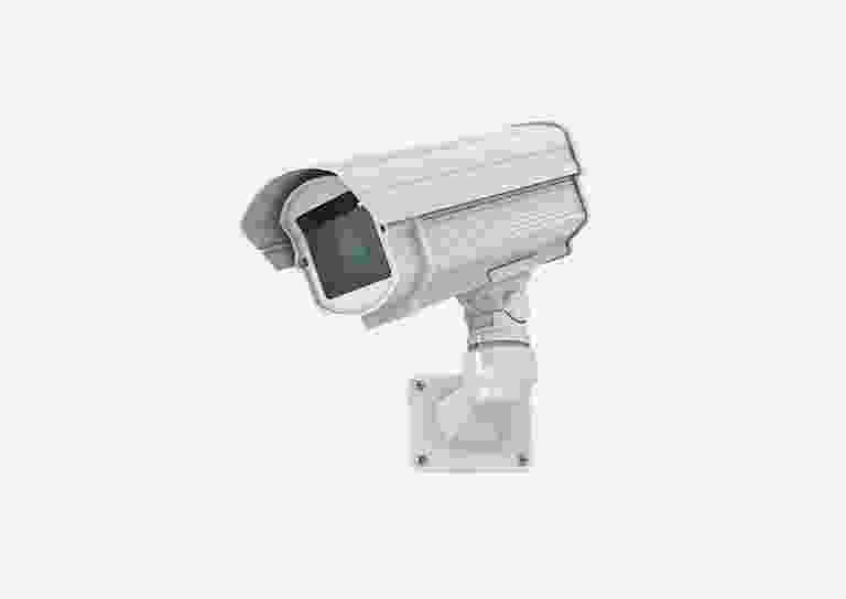 White security camera mounted on a wall. White security camera mounted on a wall.