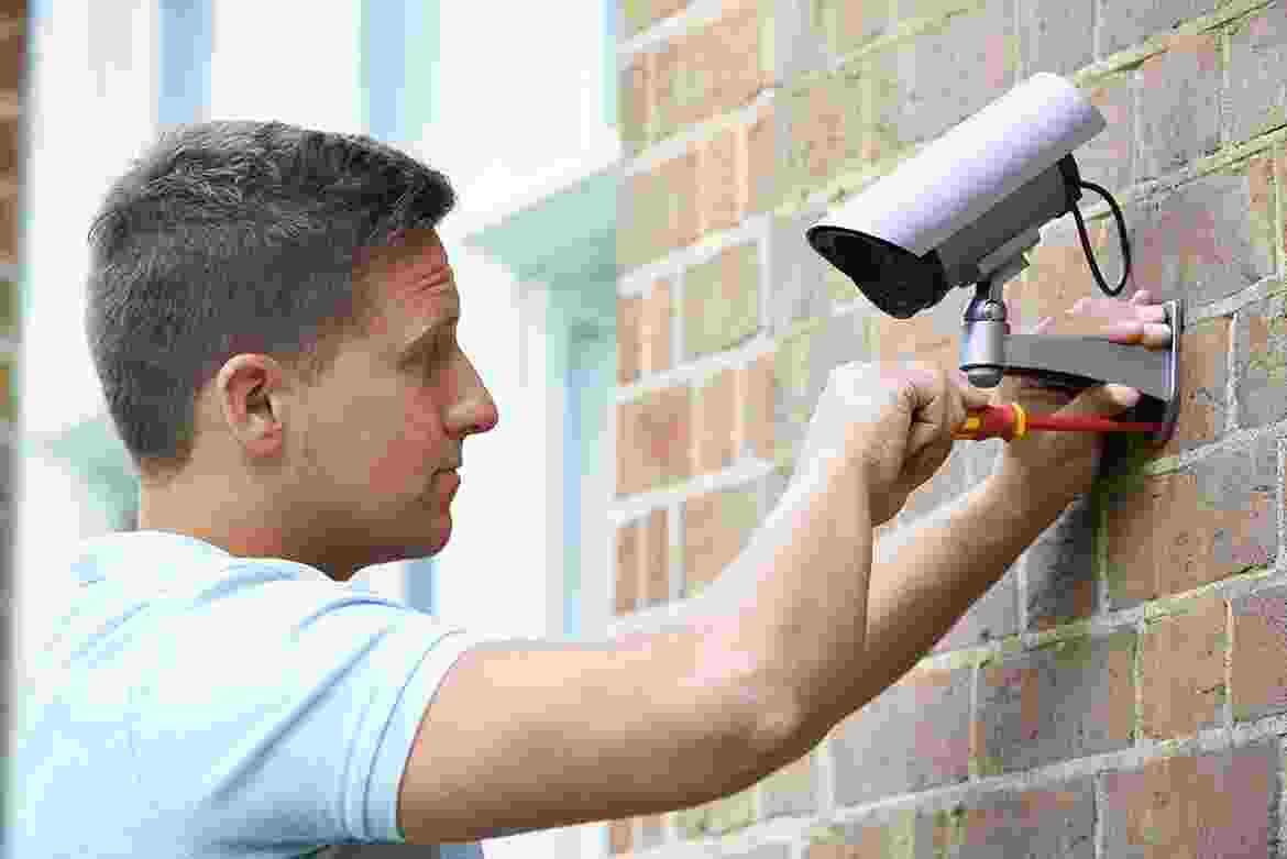 Man installing a security camera on a brick wall. Man installing a security camera on a brick wall.
