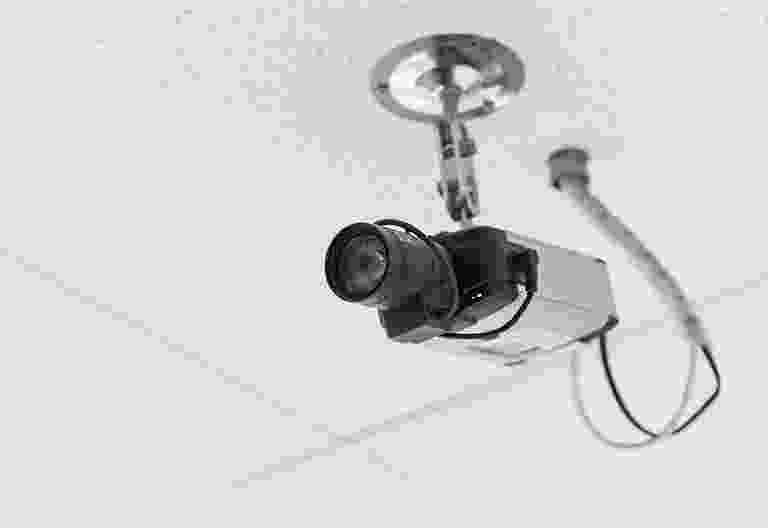 Black security camera mounted on a ceiling bracket. Black security camera mounted on a ceiling bracket.
