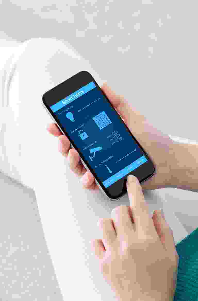Person using a mobile app to control smart home devices. Person using a mobile app to control smart home devices.