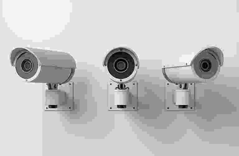 Three wall-mounted security cameras in a row. Three wall-mounted security cameras in a row.