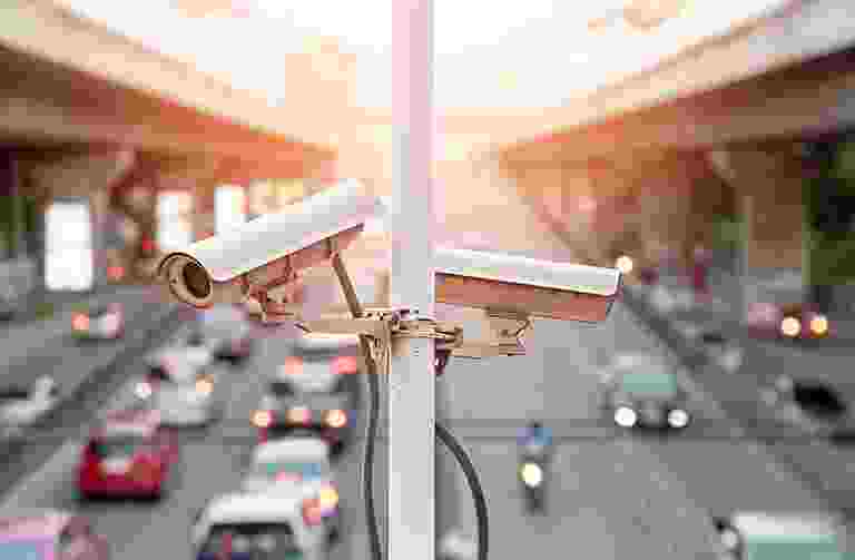 Two surveillance cameras overlooking a busy street. Two surveillance cameras overlooking a busy street.