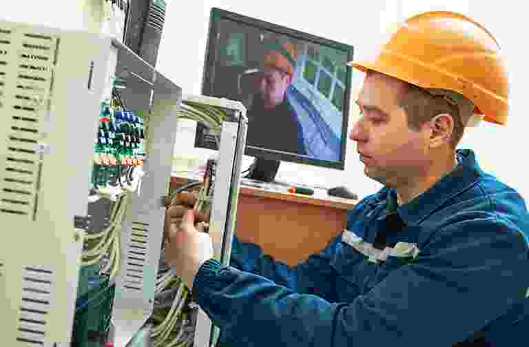 Technician working on electrical wiring with a video call in the background. Technician working on electrical wiring with a video call in the background.